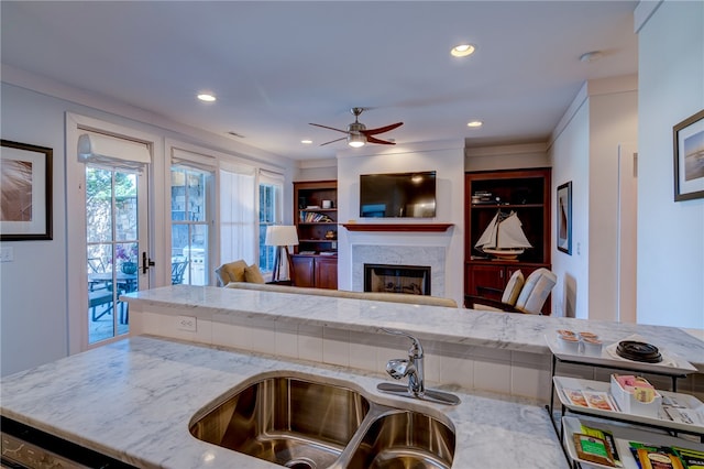 kitchen featuring ceiling fan, light stone countertops, and sink