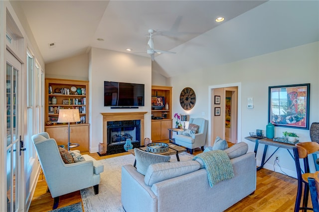 living room with a premium fireplace, vaulted ceiling, light hardwood / wood-style flooring, and ceiling fan