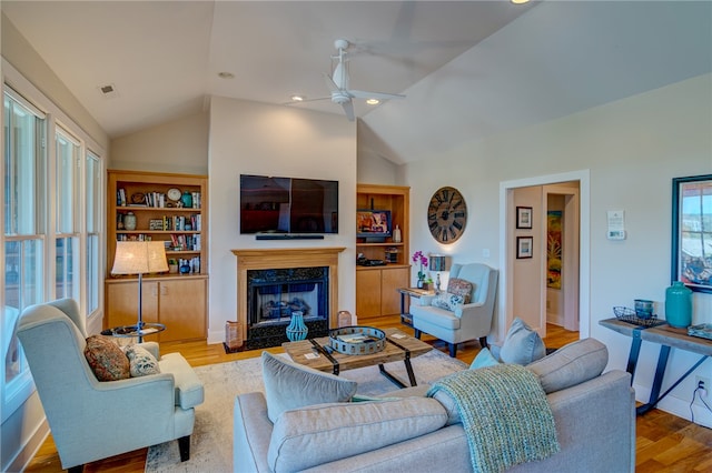 living room with ceiling fan, lofted ceiling, light hardwood / wood-style flooring, and a fireplace