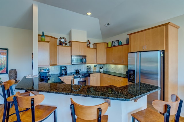 kitchen featuring light wood-type flooring, appliances with stainless steel finishes, kitchen peninsula, and decorative backsplash