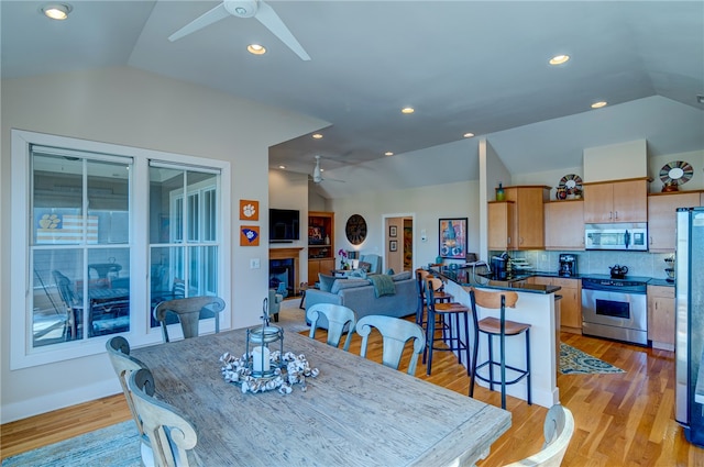 dining space with vaulted ceiling, light hardwood / wood-style floors, and ceiling fan