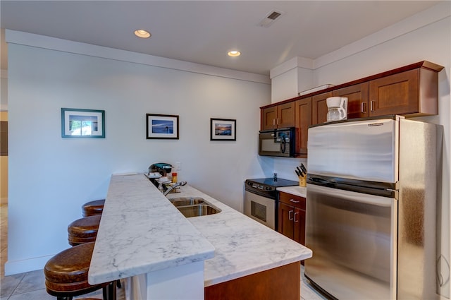 kitchen featuring appliances with stainless steel finishes, light tile patterned flooring, sink, and a kitchen bar