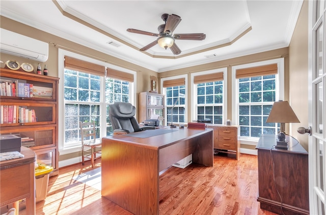 office with a wall mounted air conditioner, light wood-type flooring, a tray ceiling, ceiling fan, and crown molding