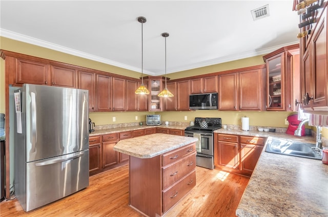 kitchen with a center island, stainless steel appliances, light hardwood / wood-style flooring, crown molding, and pendant lighting