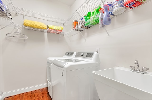 laundry room featuring washing machine and dryer, sink, and wood-type flooring