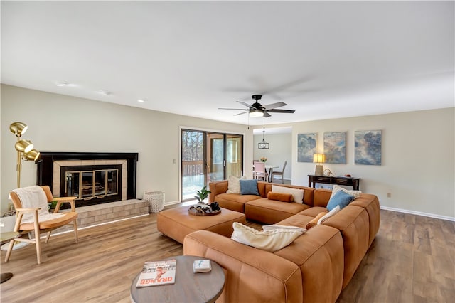 living room with ceiling fan, light hardwood / wood-style flooring, and a tile fireplace