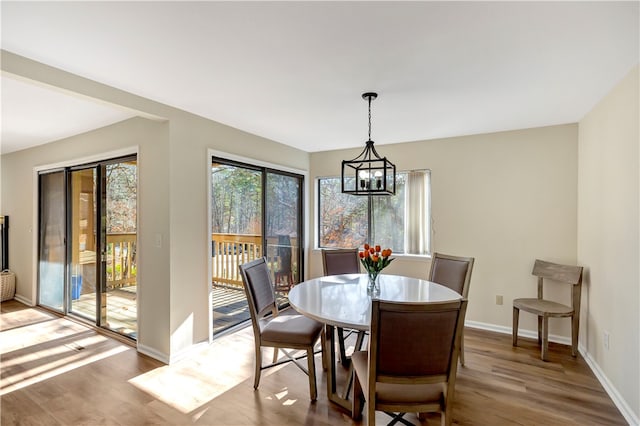 dining space featuring wood-type flooring and an inviting chandelier