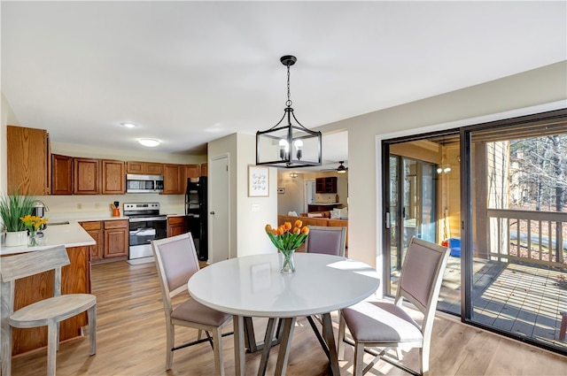 dining space with sink, a notable chandelier, and light hardwood / wood-style flooring