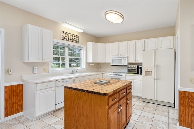 kitchen with light tile patterned flooring, white appliances, sink, a kitchen island, and white cabinetry