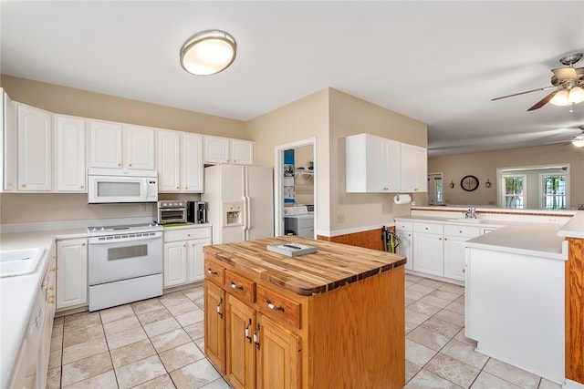 kitchen featuring kitchen peninsula, white appliances, washer / dryer, a center island, and white cabinetry