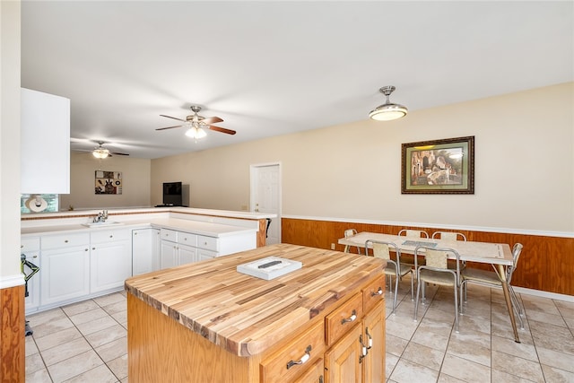 kitchen with sink, white cabinetry, kitchen peninsula, and wooden walls