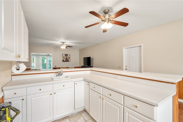 kitchen featuring kitchen peninsula, sink, ceiling fan, light tile patterned floors, and white cabinetry