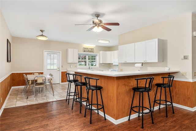 kitchen featuring white cabinets, a kitchen breakfast bar, light wood-type flooring, and kitchen peninsula