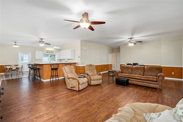 living room featuring ceiling fan, wood walls, and dark hardwood / wood-style flooring