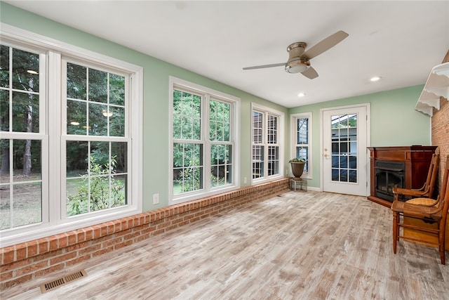 unfurnished sunroom featuring ceiling fan and a healthy amount of sunlight