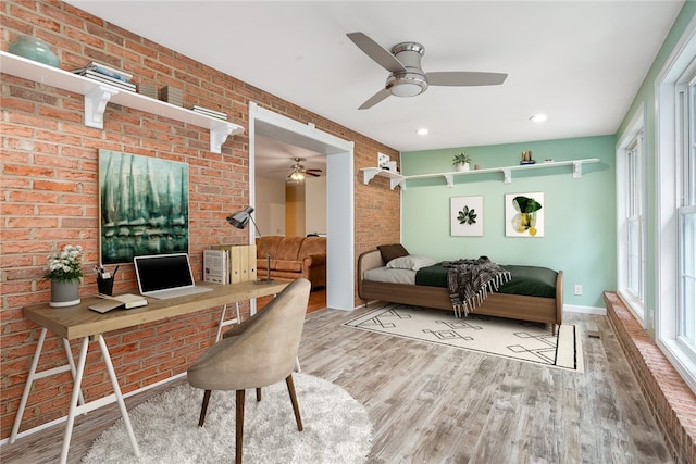 office area featuring ceiling fan, light wood-type flooring, and brick wall