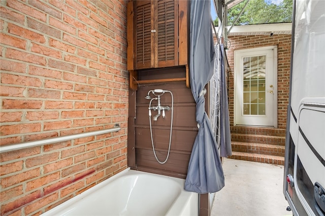 bathroom with a tub and brick wall