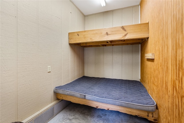 mudroom featuring wood walls and concrete flooring