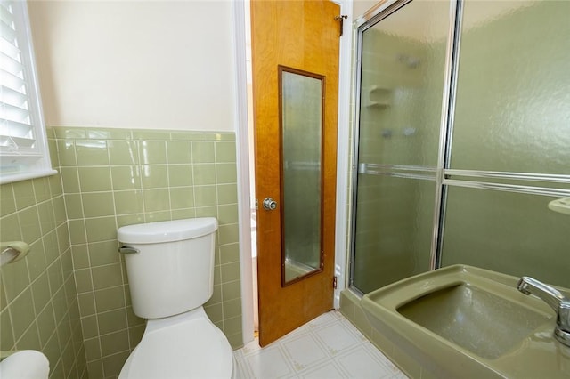 bathroom featuring tile walls, an enclosed shower, and toilet