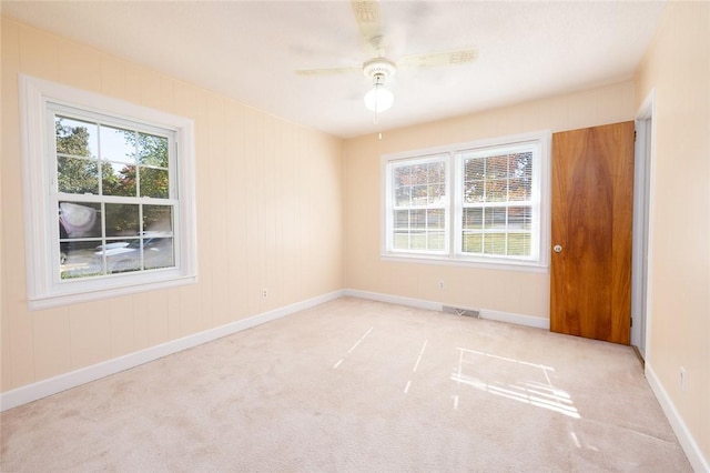 empty room with ceiling fan, light carpet, and a healthy amount of sunlight