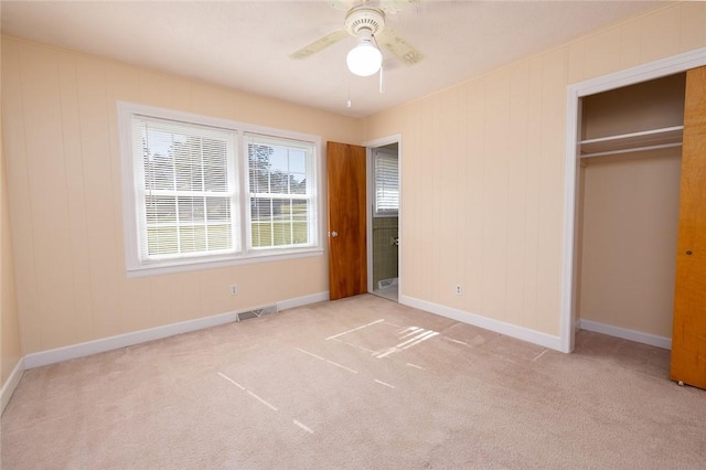 unfurnished bedroom featuring ceiling fan, light carpet, and a closet