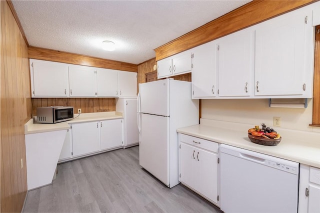 kitchen featuring white appliances, white cabinetry, and wood walls