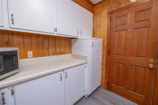 clothes washing area featuring wood walls and light hardwood / wood-style flooring