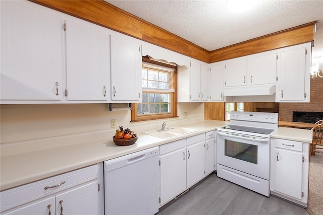 kitchen with white appliances, sink, light wood-type flooring, white cabinetry, and a textured ceiling