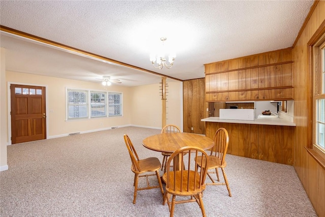 carpeted dining room featuring wood walls and a textured ceiling