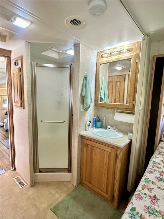 bathroom featuring vanity, a shower with shower door, and tile patterned flooring