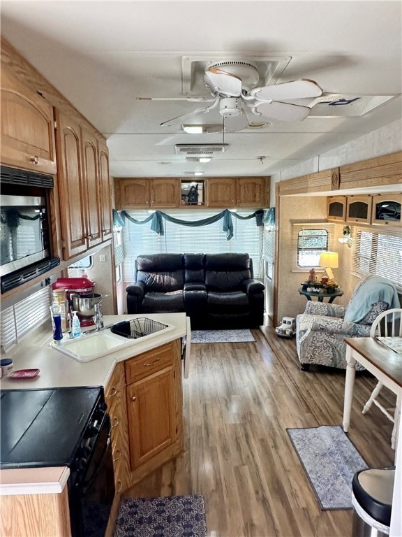 kitchen with light hardwood / wood-style floors, stainless steel microwave, ceiling fan, and black electric range