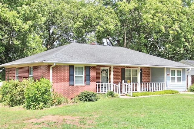 ranch-style home featuring covered porch and a front lawn