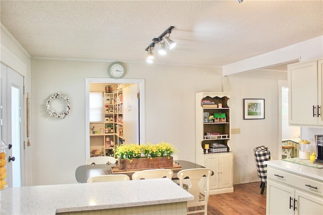 kitchen with light stone countertops, a textured ceiling, light hardwood / wood-style floors, and white cabinetry