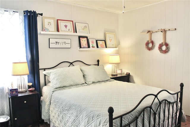 bedroom with crown molding, wooden walls, and wood-type flooring