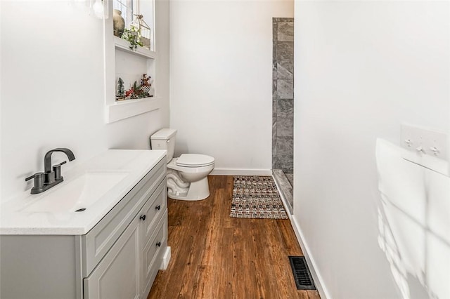 bathroom with hardwood / wood-style floors, vanity, toilet, and walk in shower