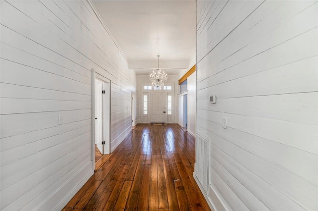 hallway featuring a chandelier, dark hardwood / wood-style floors, and wood walls