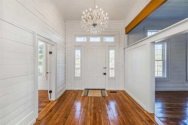 foyer entrance with a chandelier, a healthy amount of sunlight, and dark wood-type flooring