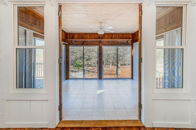 doorway to outside featuring ceiling fan and wooden walls