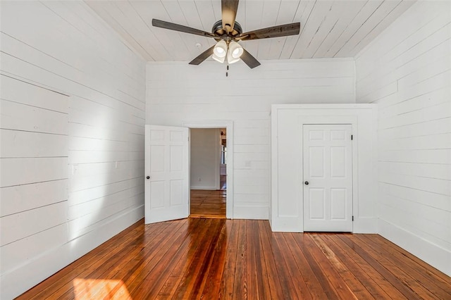 unfurnished bedroom featuring wooden ceiling, ceiling fan, dark wood-type flooring, and wood walls