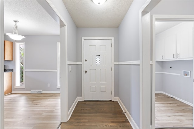 entryway with a textured ceiling and wood-type flooring