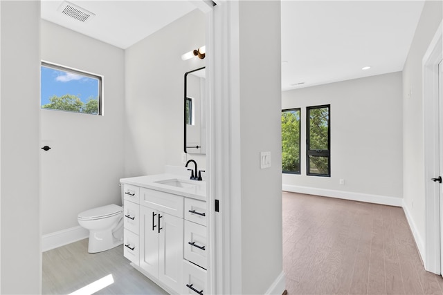 bathroom featuring toilet, hardwood / wood-style floors, vanity, and plenty of natural light