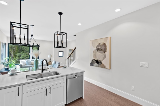 kitchen with light hardwood / wood-style flooring, hanging light fixtures, sink, stainless steel dishwasher, and white cabinetry