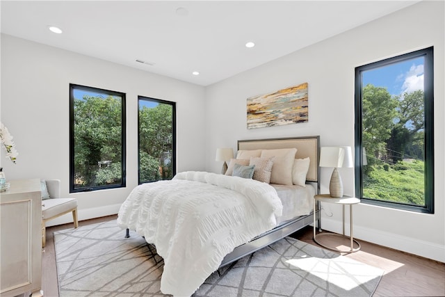 bedroom with multiple windows and light hardwood / wood-style floors