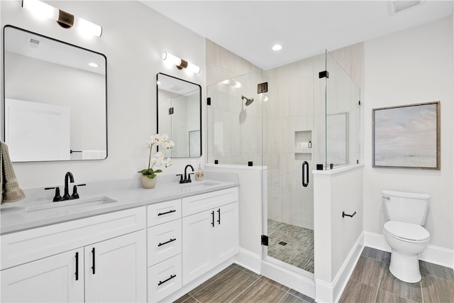 bathroom with a shower with door, toilet, and vanity