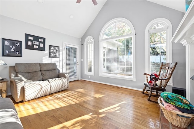 living room with ornate columns, wood-type flooring, high vaulted ceiling, and ceiling fan