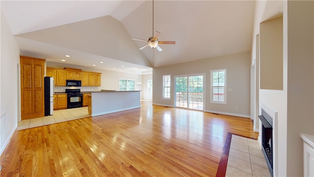 unfurnished living room with ceiling fan, high vaulted ceiling, and light wood-type flooring