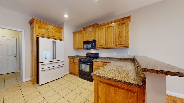 kitchen with dark stone countertops, black appliances, kitchen peninsula, and light tile patterned flooring