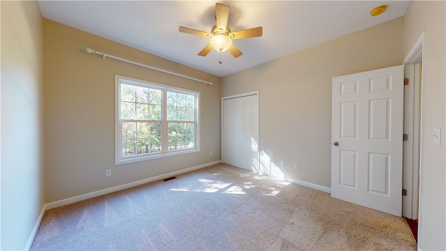 unfurnished bedroom featuring ceiling fan, light colored carpet, and a closet