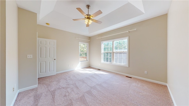 carpeted empty room featuring ceiling fan and a raised ceiling