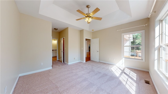 unfurnished bedroom featuring light colored carpet, a raised ceiling, and ensuite bathroom